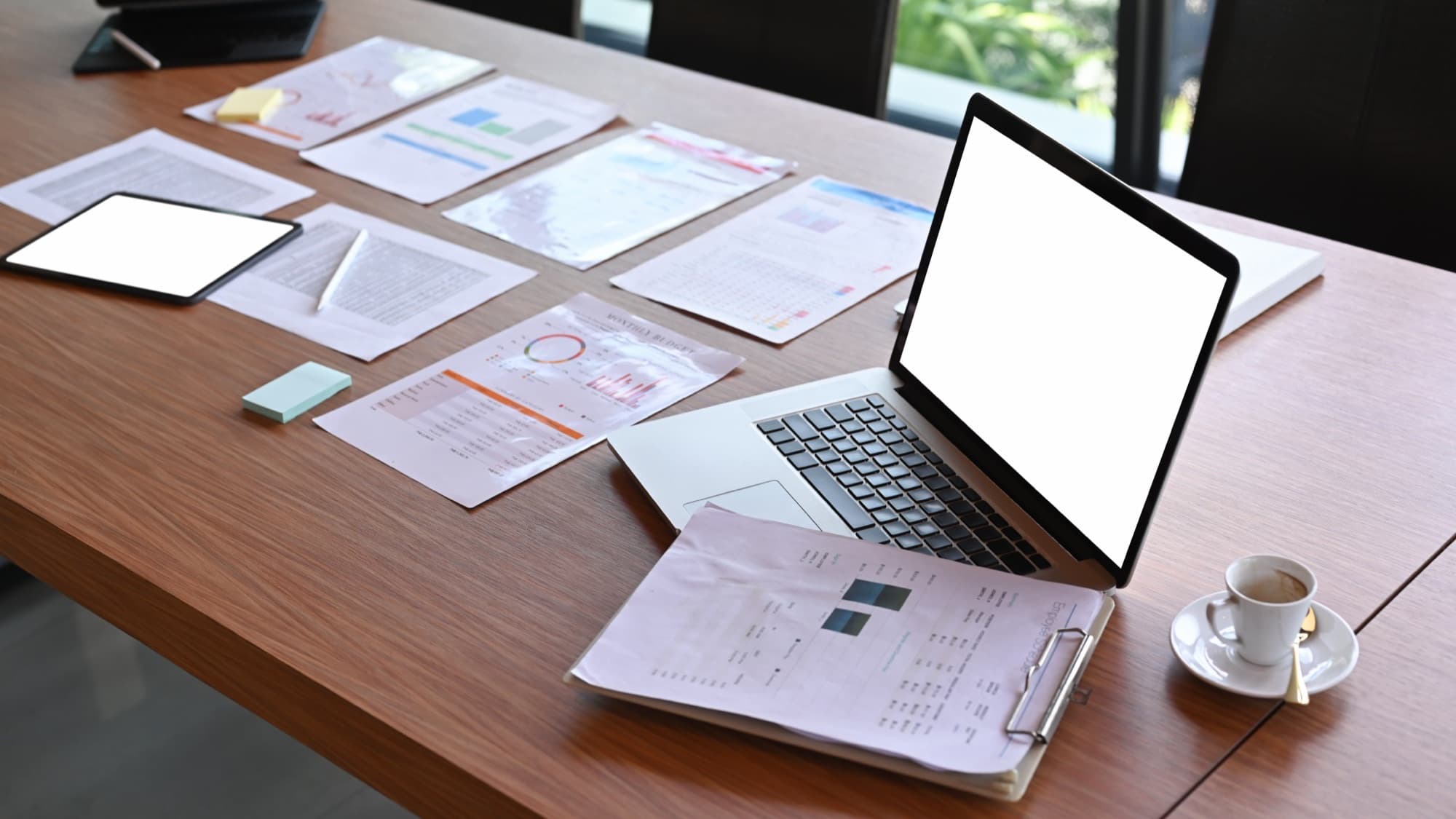 Laptop, coffee and printed documents on a table.