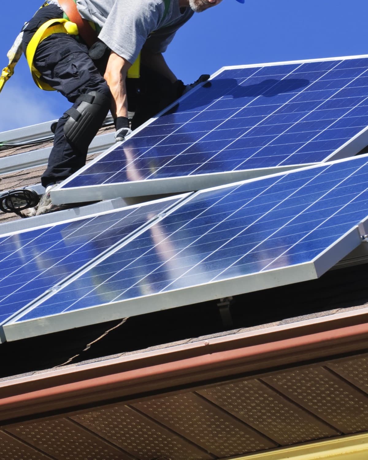 Roofer installing solar panels on a house.
