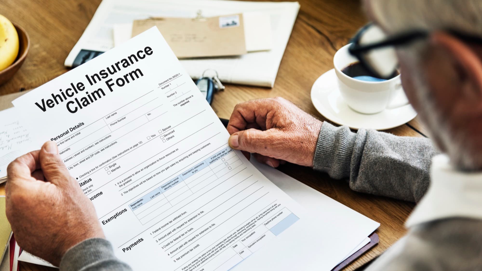 Senior filling out vehicle insurance claim form.