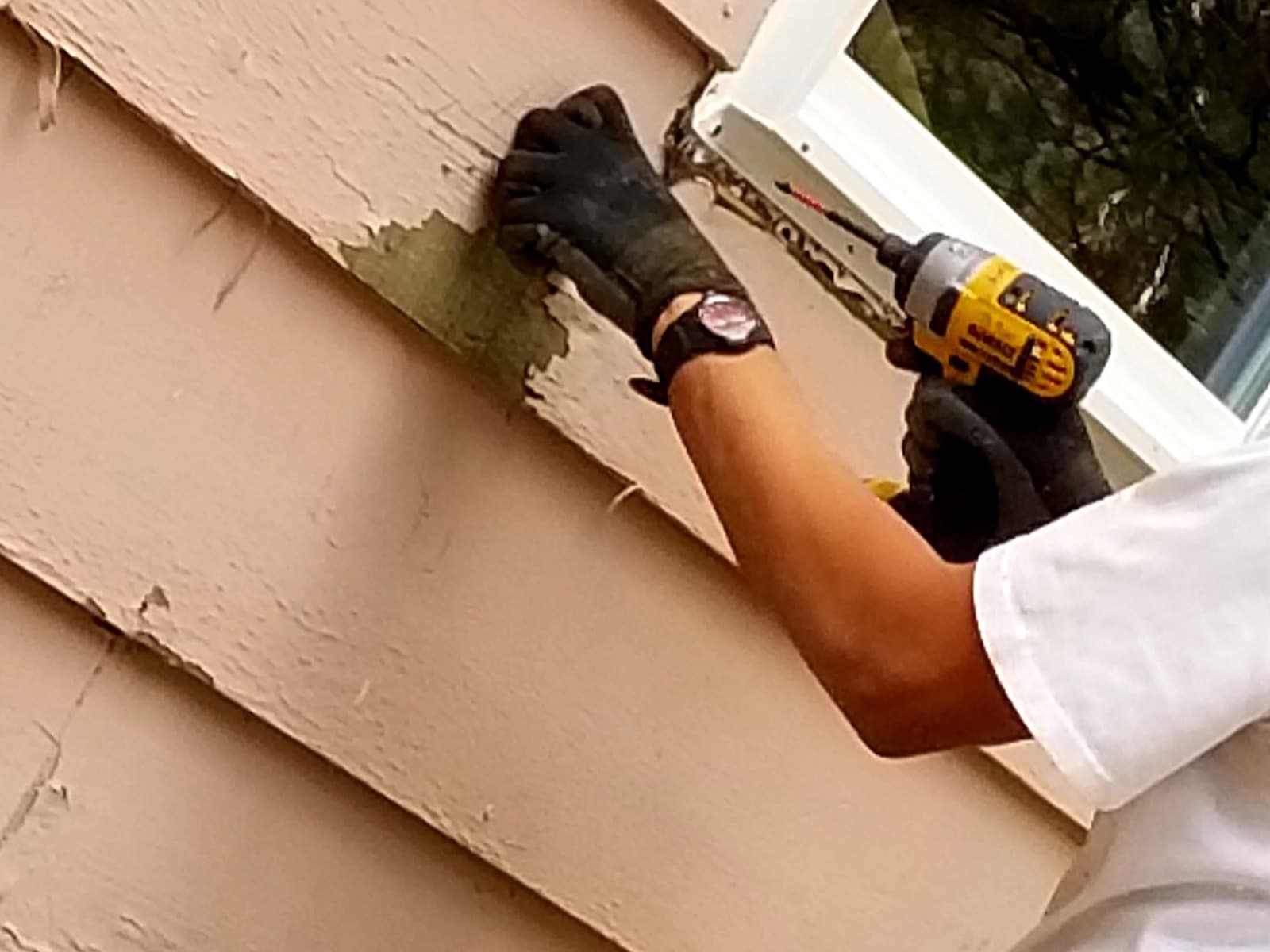 Man repairing house siding with a power tool.